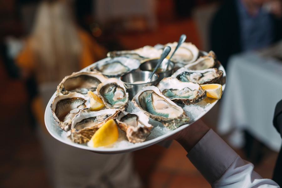 Server bringing oysters to restaurant table