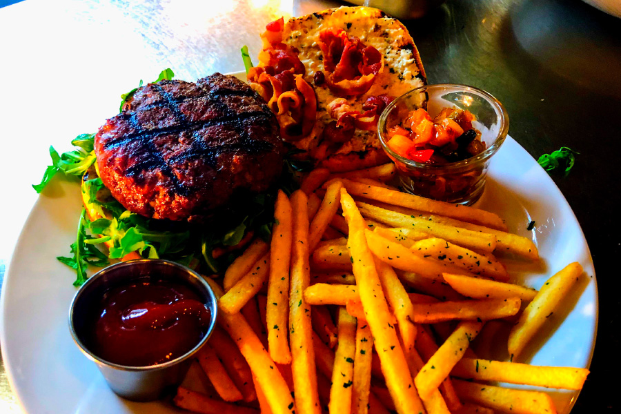 Plated burger with fries and dipping sauce at Feast, Bozeman